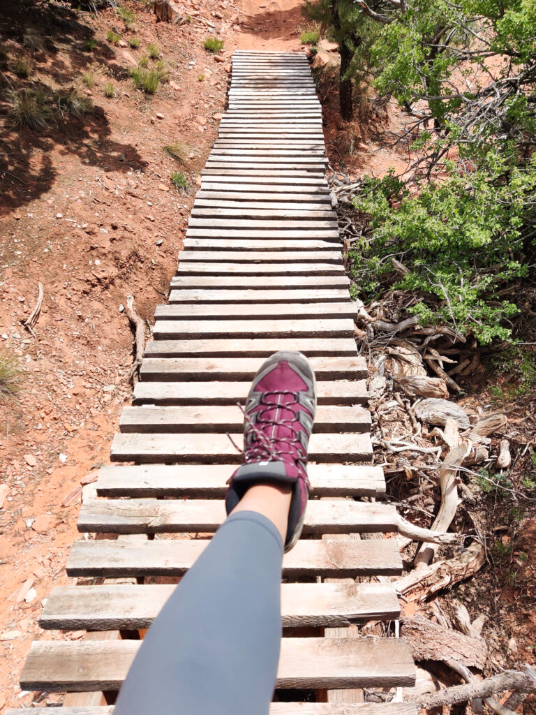 woman hiking a slated bridge  wearing a hiking boot 