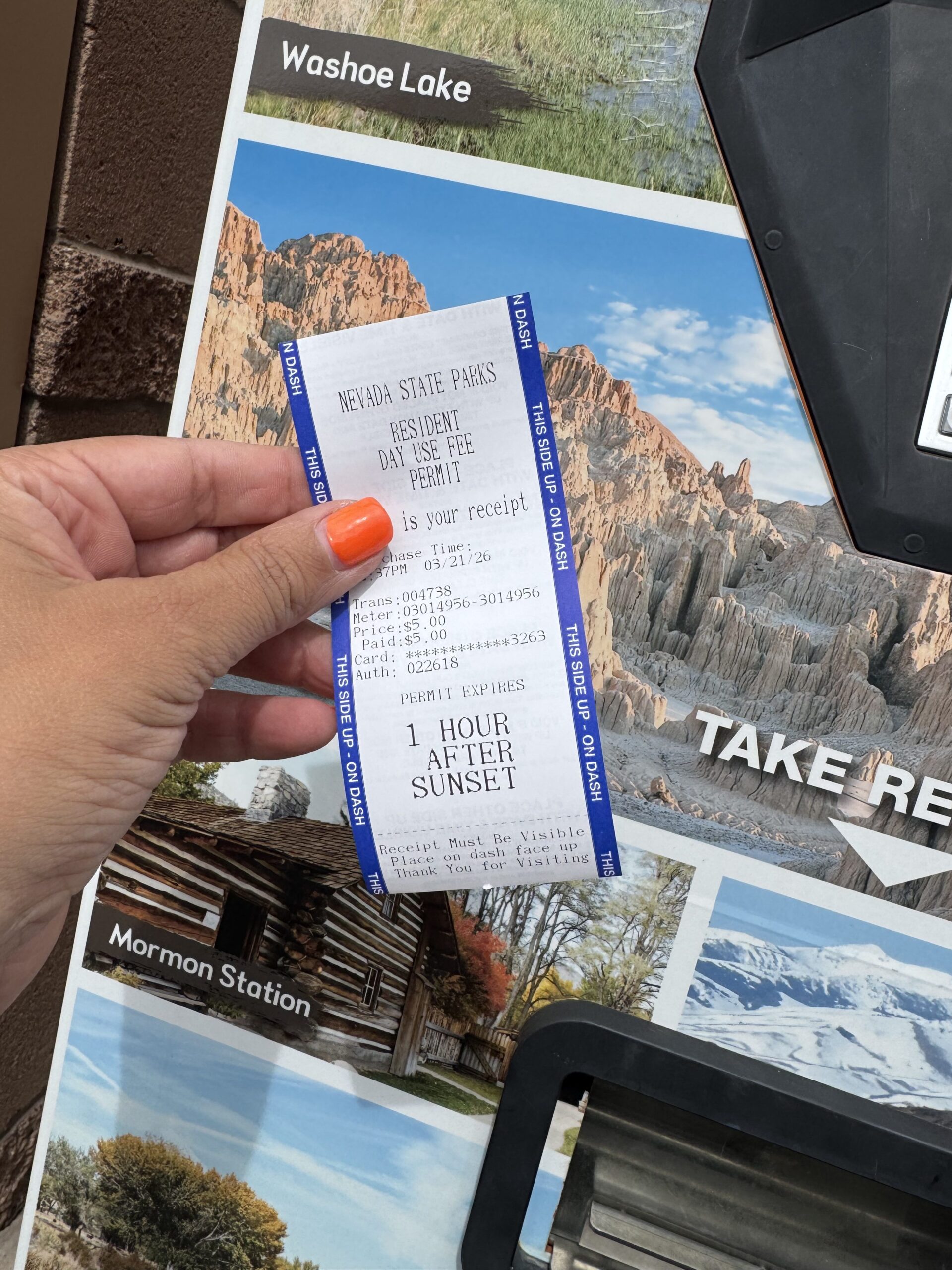 hand holding day pass for state park in nevada in front of ticket kiosk