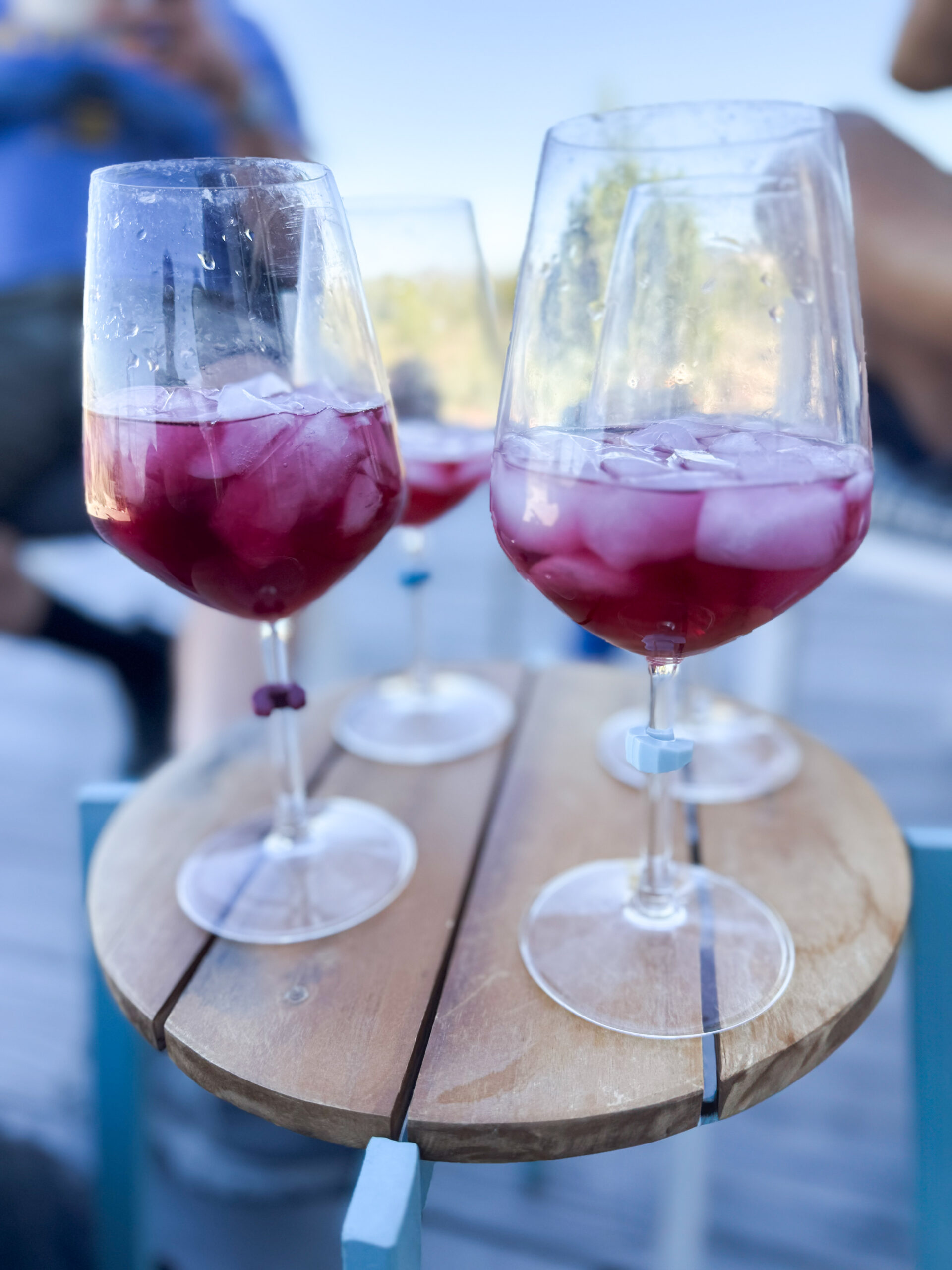 four wine glasses with ice and sangria on a wodden table outside