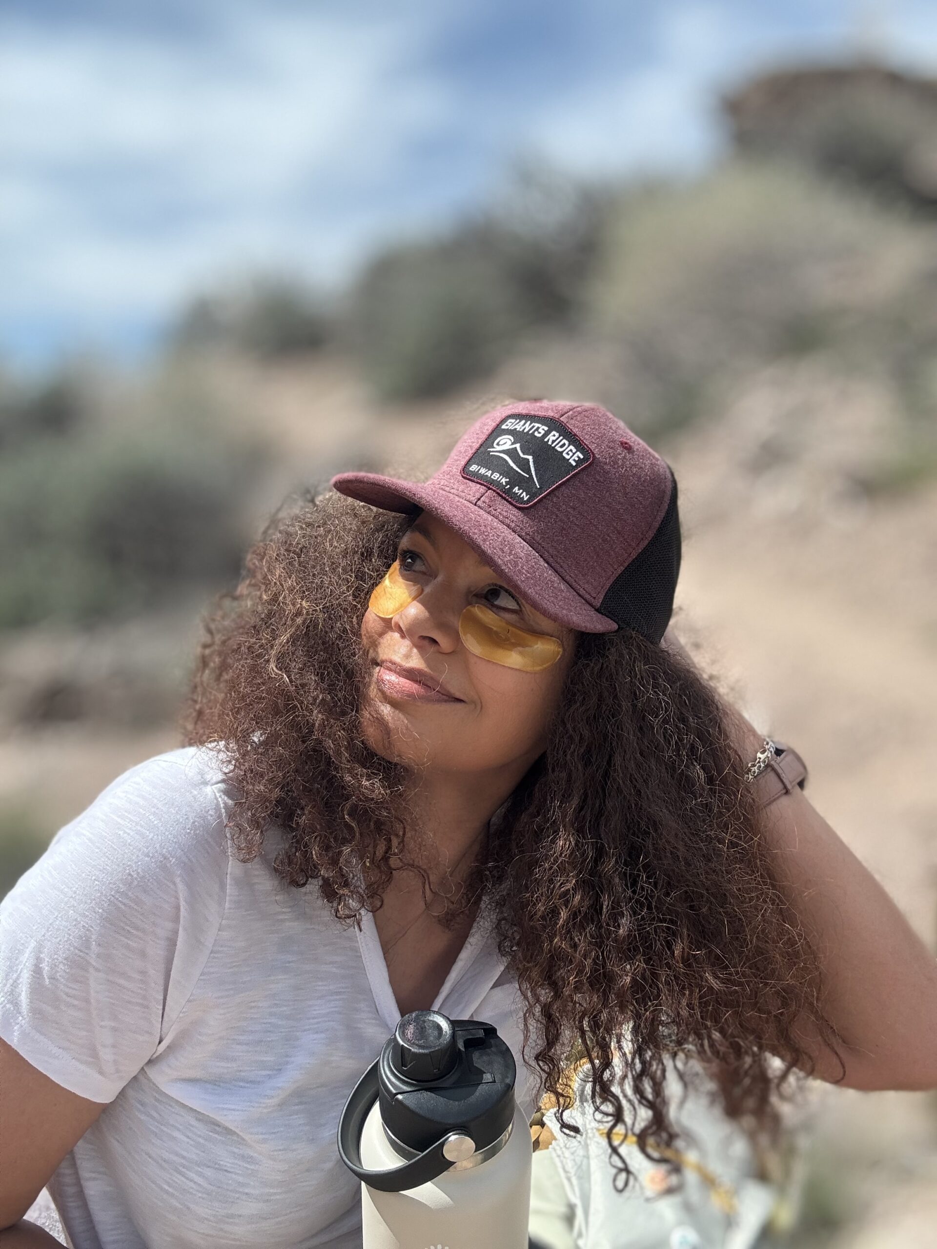 black woman wearing eye patches and wearing a hat on hike for post hike reset