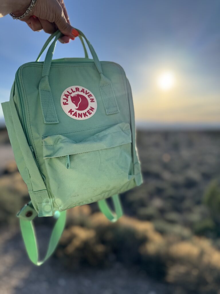 green mini backpack with sunrise in the backgrouns