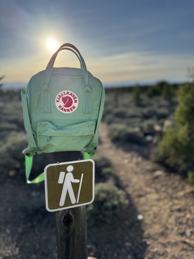 green backpack on top of trailhead sign in Nevada desert landscape