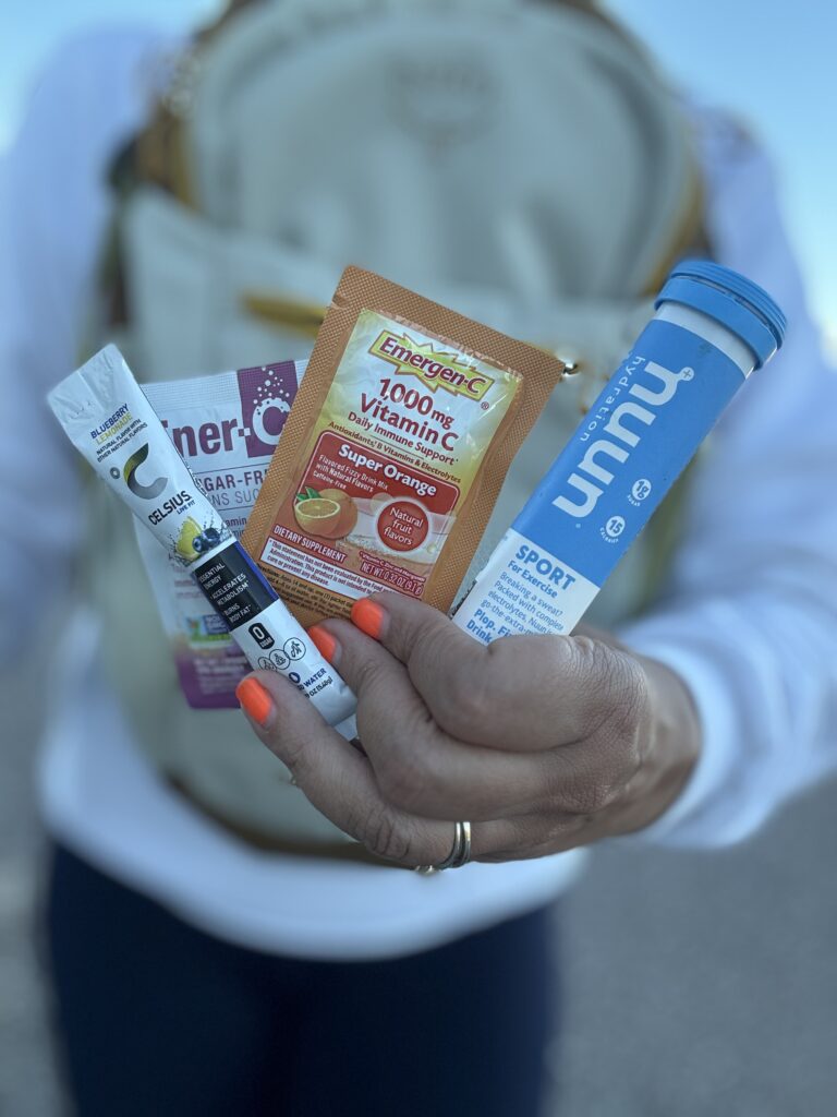 hand holding a variety of electrolyte packets in front of back pack