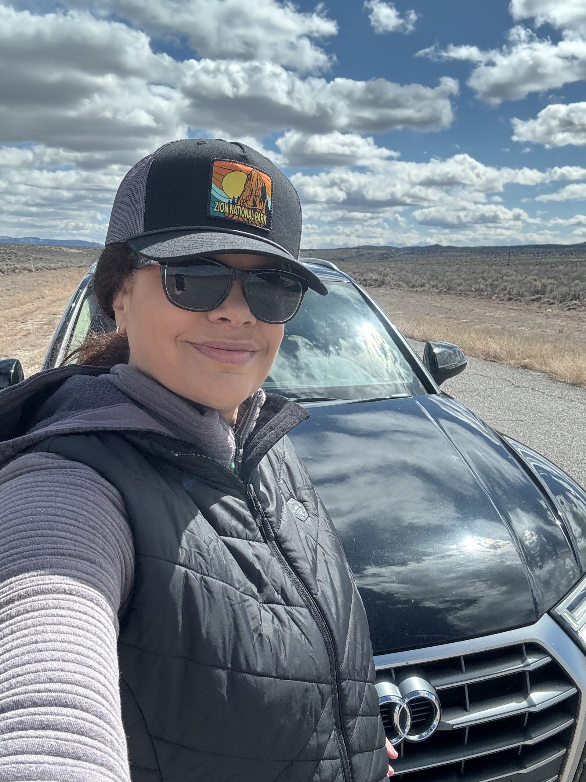 black woman wearing baseball hat on road tip on desert road