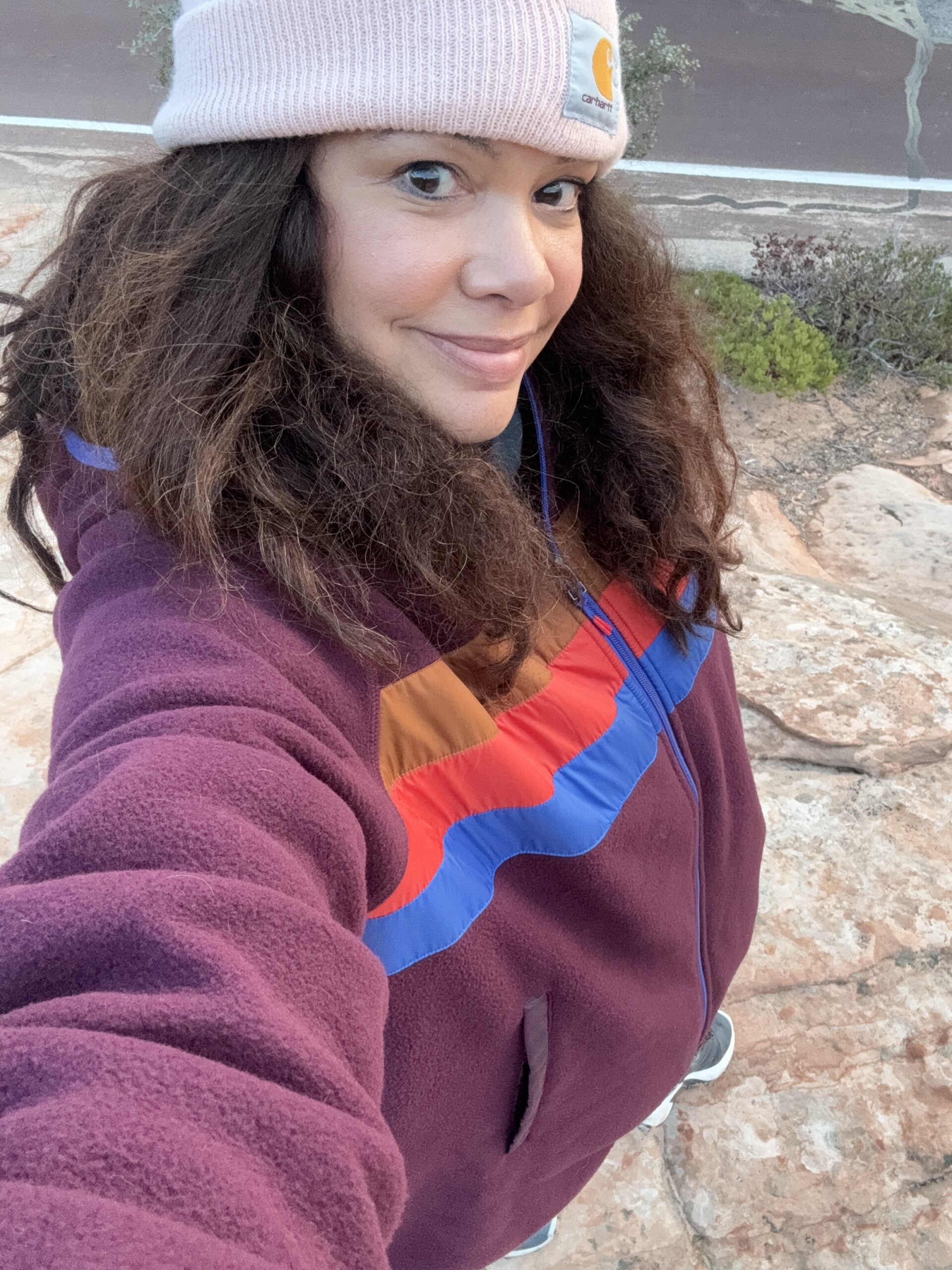 black woman in feece jacket and pink beanie smiling at camera in bryce canyon