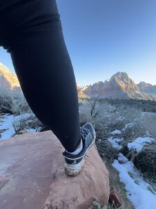 shoe at end of leg planted on a rock looking at the view of Zion Nation Park