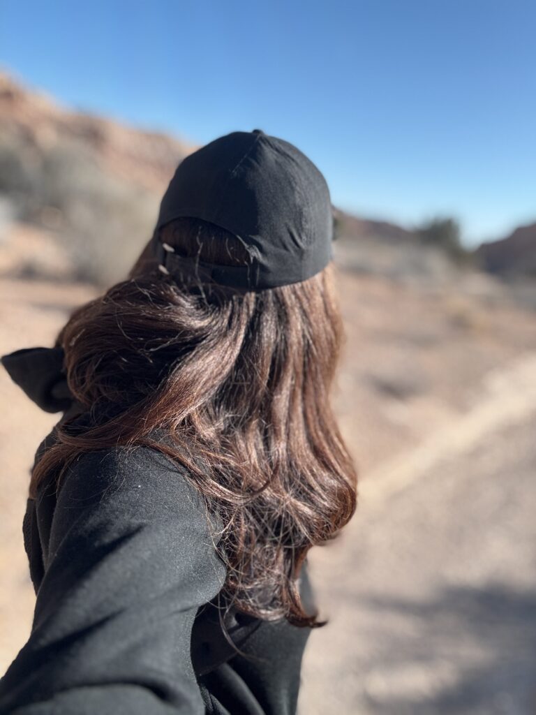 woman wearing black black baseball hat on a hike in the desert landscape