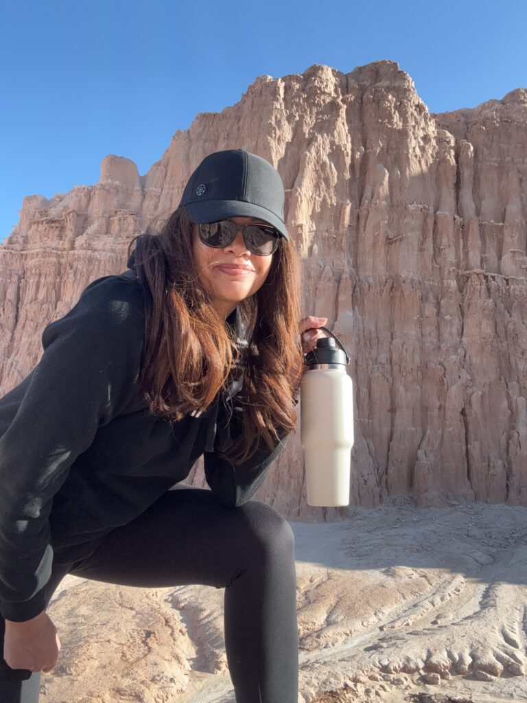 black woman holding water bottle on hike in desert landscape