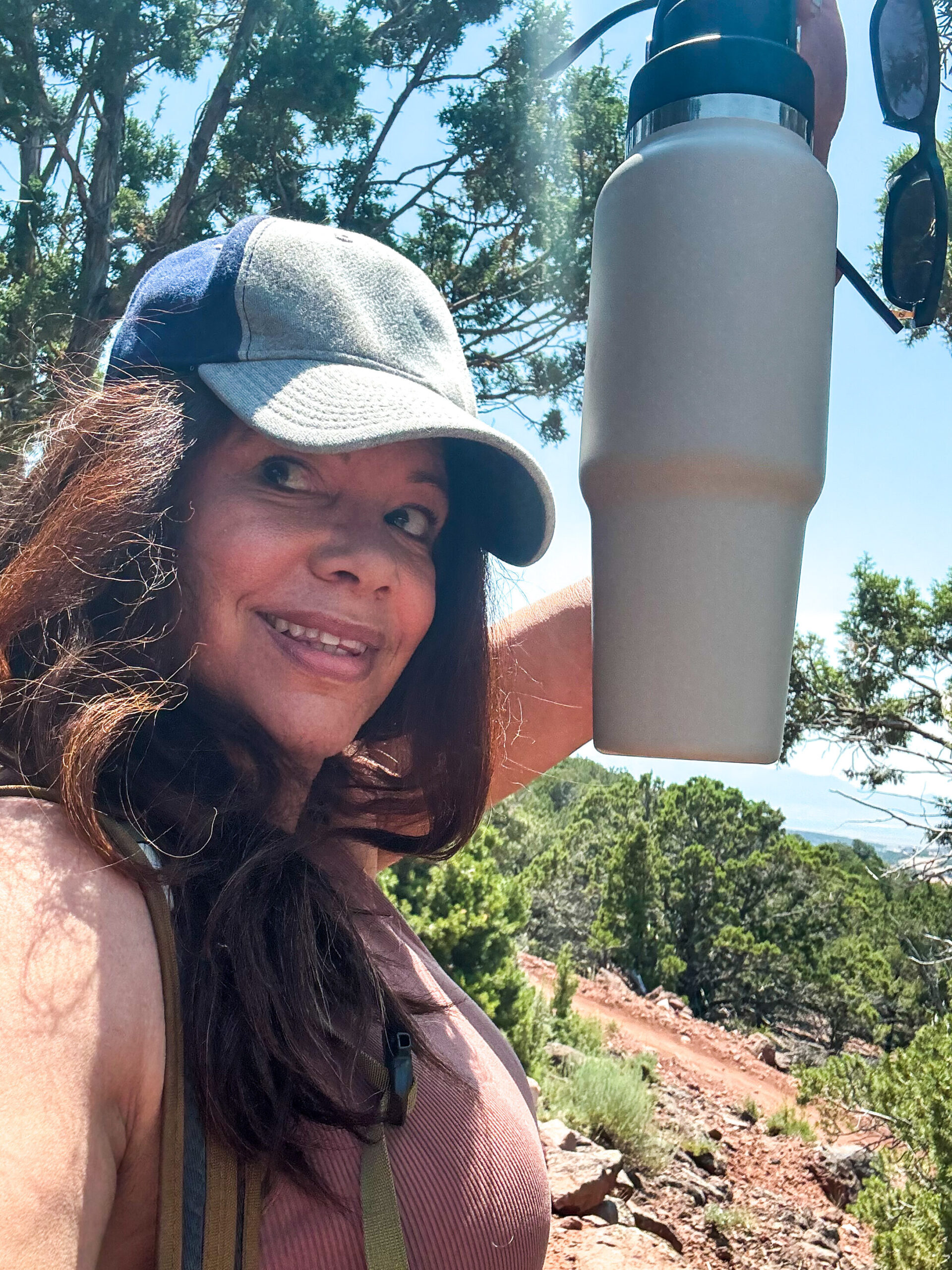 black woman in baseball hat holding water bottle above head