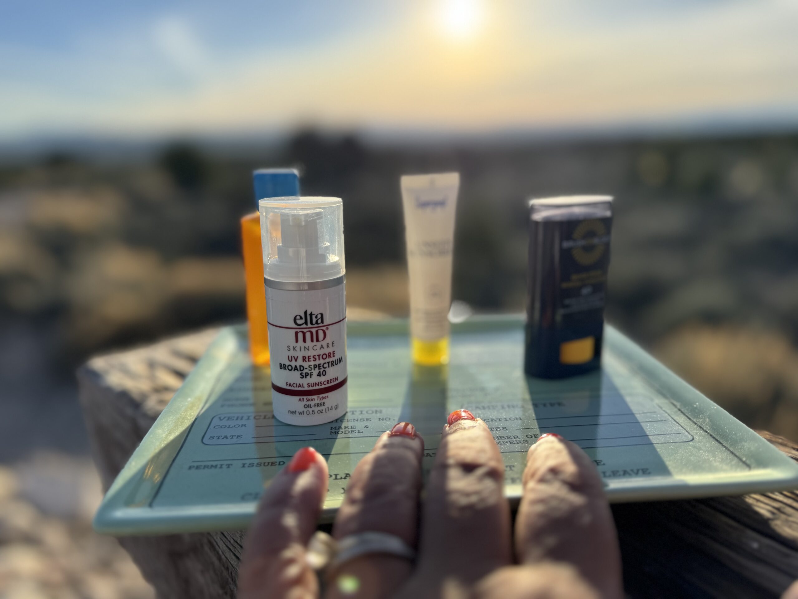 hand reaching for plate of sunscreen option on plate with sunset in background