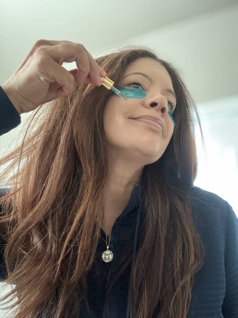 black woman over 35 applying sunscreen and skincare products while wearing eye patched for skincare routine